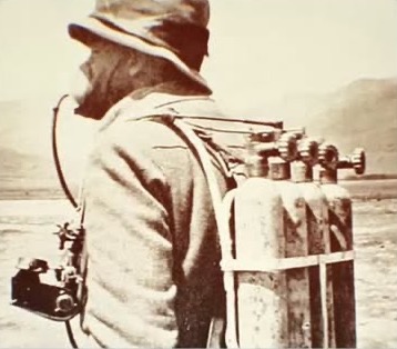 Photographie d'archive : un alpiniste de dos portant les bouteilles d'oxygène de 1924
