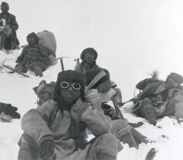 Photographie d'archive : les sherpas de l'expédition assis dans la neige, lunettes de glacier